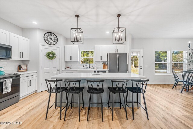 kitchen with white cabinetry, appliances with stainless steel finishes, and a kitchen island with sink