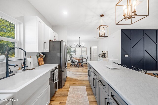 kitchen featuring pendant lighting, white cabinetry, backsplash, light hardwood / wood-style floors, and an inviting chandelier