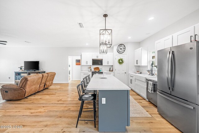 kitchen with white cabinetry, appliances with stainless steel finishes, decorative light fixtures, and a center island