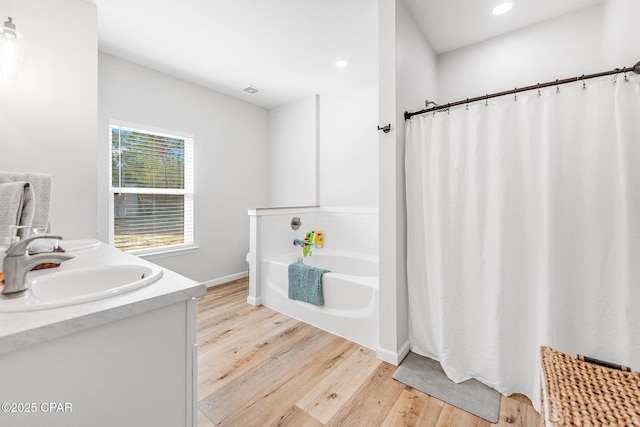 bathroom with a bathing tub, wood-type flooring, and vanity