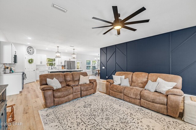 living room with ceiling fan, sink, and light hardwood / wood-style floors