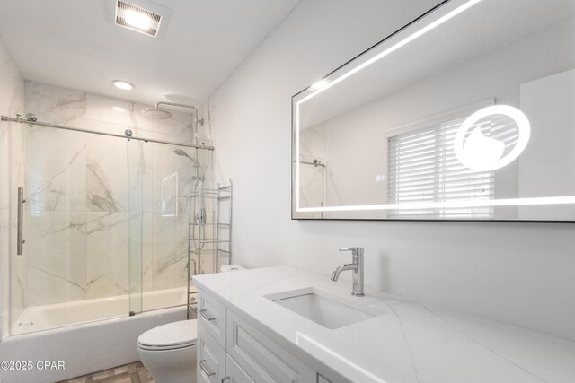 full bathroom featuring vanity, combined bath / shower with glass door, and toilet