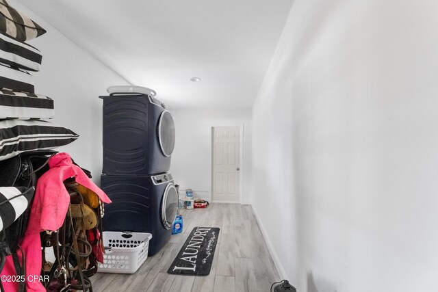 clothes washing area with stacked washer and dryer and light wood-type flooring