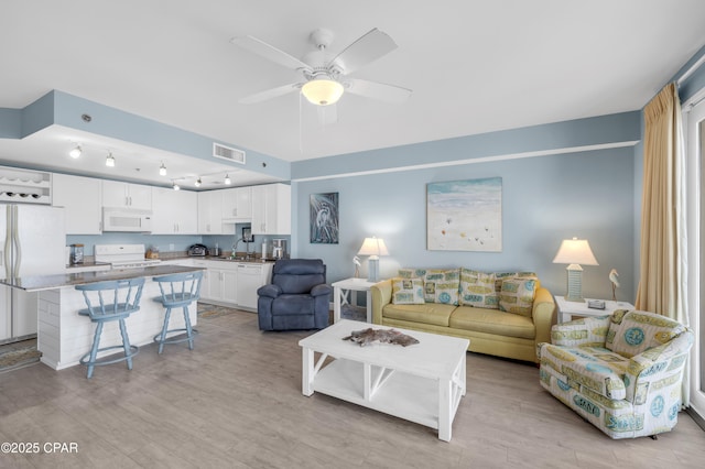 living room with ceiling fan, sink, and light hardwood / wood-style flooring