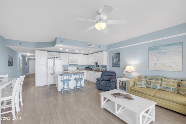 living room featuring ceiling fan, sink, and light hardwood / wood-style flooring