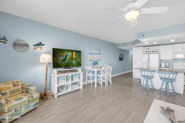 living room with ceiling fan and light hardwood / wood-style flooring