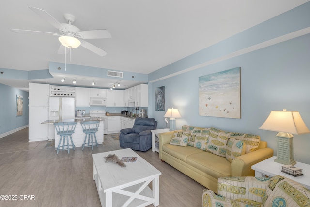 living room with ceiling fan, sink, and light wood-type flooring