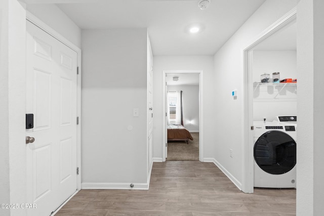 clothes washing area featuring washer / clothes dryer and light hardwood / wood-style flooring