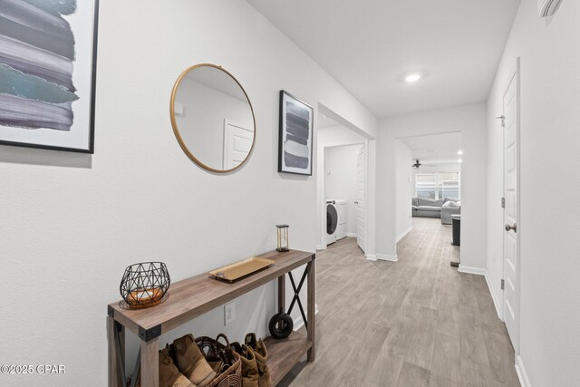 hall with washer / dryer and light hardwood / wood-style flooring