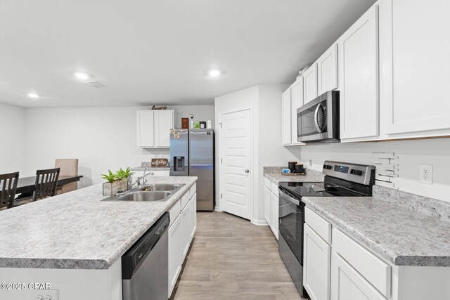 kitchen with a kitchen island with sink, sink, white cabinetry, and stainless steel appliances