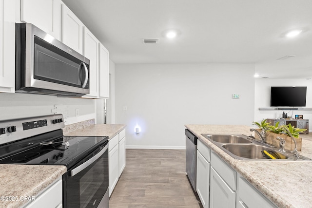 kitchen featuring white cabinetry, appliances with stainless steel finishes, sink, and light wood-type flooring