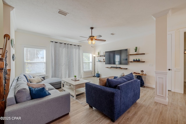 living room with ornamental molding, a textured ceiling, and light wood-type flooring