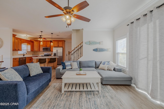 living room featuring light hardwood / wood-style flooring, ornamental molding, and ceiling fan