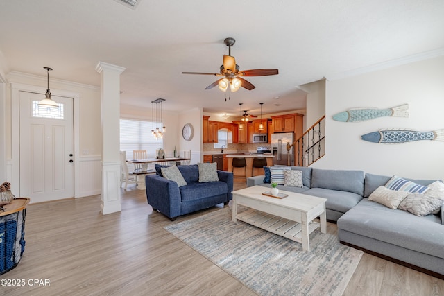 living room with ornamental molding, decorative columns, ceiling fan, and light wood-type flooring