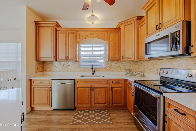 kitchen with sink, backsplash, ceiling fan, stainless steel appliances, and light hardwood / wood-style flooring