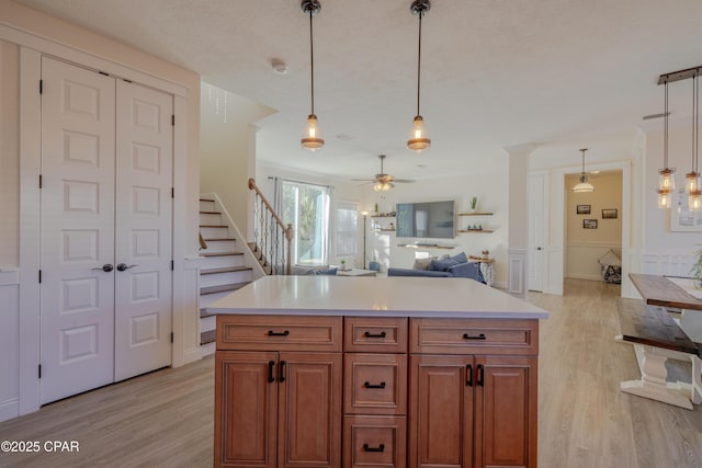 kitchen featuring pendant lighting, a textured ceiling, a kitchen island, and light wood-type flooring