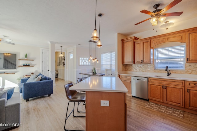 kitchen featuring sink, hanging light fixtures, dishwasher, a kitchen island, and a wealth of natural light