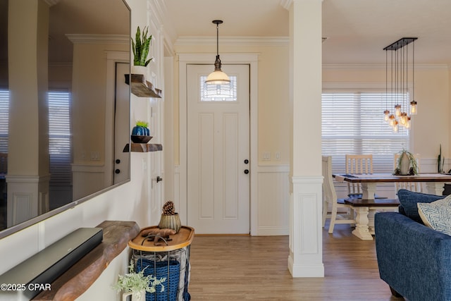 entrance foyer with crown molding, light hardwood / wood-style flooring, and ornate columns