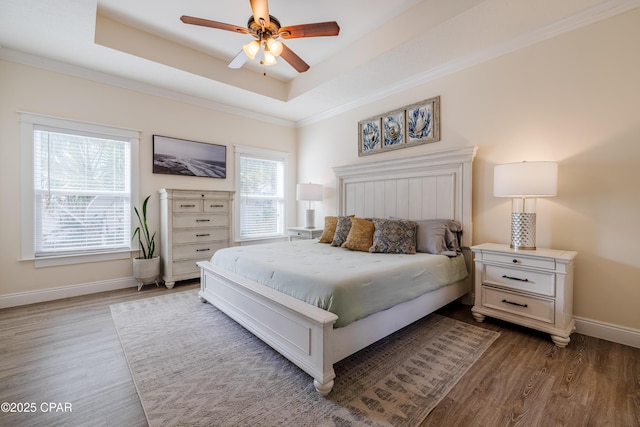 bedroom featuring hardwood / wood-style flooring, ceiling fan, crown molding, and a raised ceiling