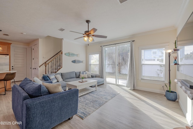 living room with a textured ceiling, light hardwood / wood-style flooring, ornamental molding, and ceiling fan