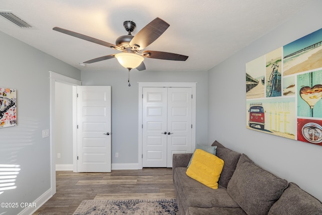 sitting room with ceiling fan and wood-type flooring