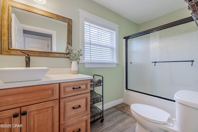 full bathroom featuring toilet, vanity, shower / bath combination with glass door, and hardwood / wood-style floors