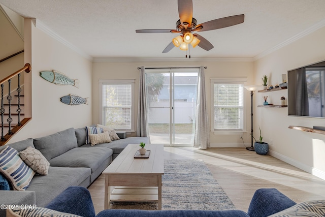 living room featuring crown molding, ceiling fan, light wood-type flooring, and a wealth of natural light