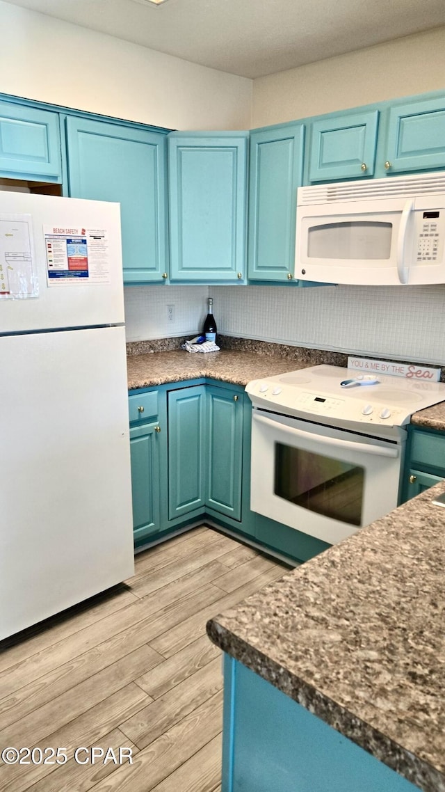 kitchen featuring dark countertops, white appliances, light wood-type flooring, and blue cabinetry