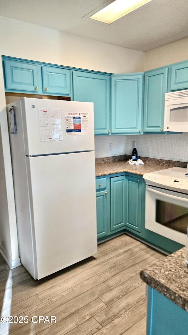 kitchen with white appliances, dark countertops, blue cabinetry, and light wood-style floors