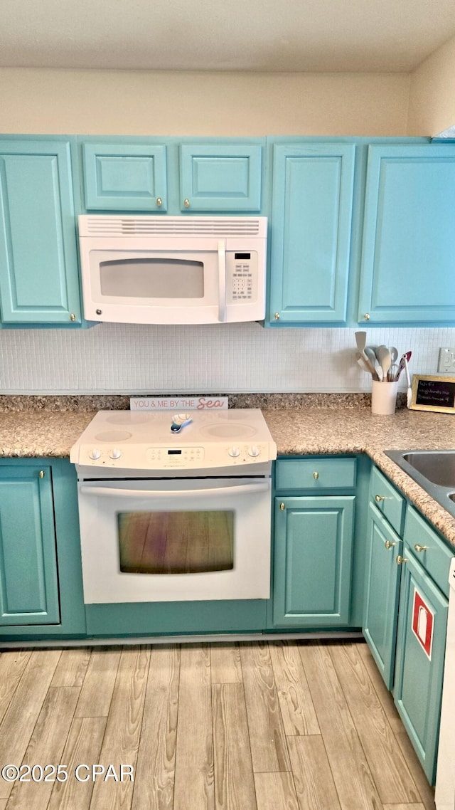 kitchen featuring white appliances, light countertops, a sink, and light wood-style flooring