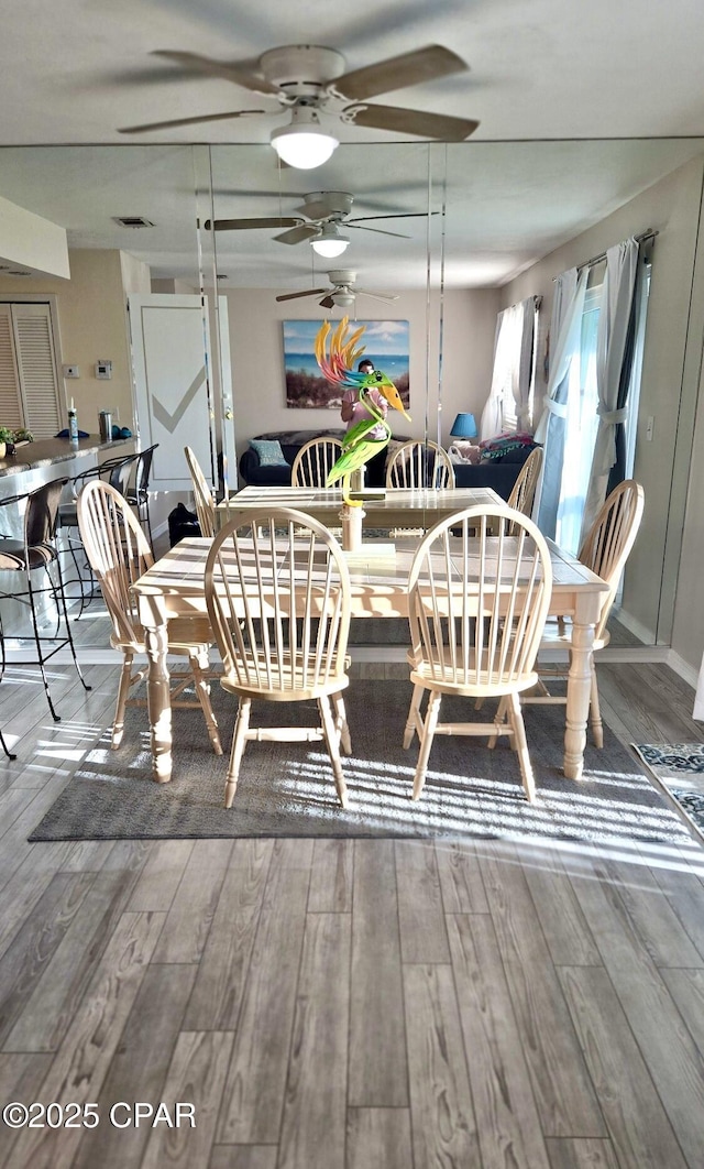 dining area with ceiling fan, wood finished floors, and visible vents