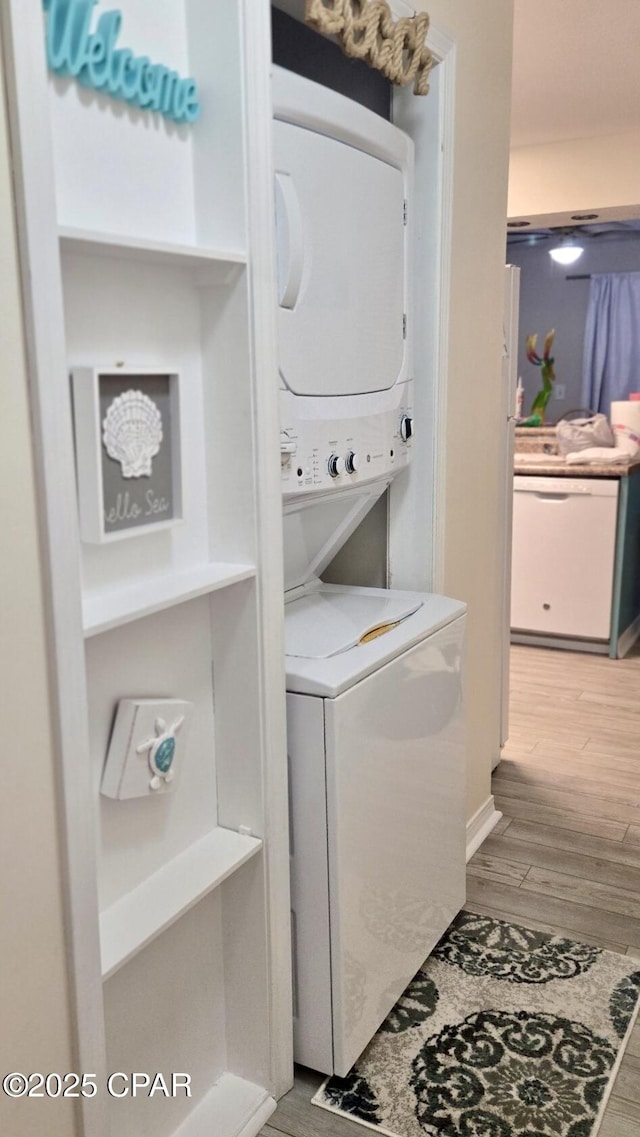 laundry room featuring stacked washing maching and dryer, laundry area, and light wood-style floors