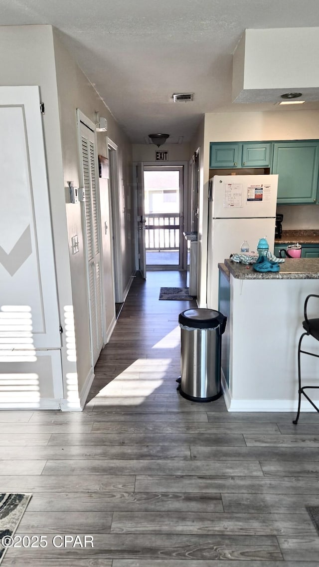 hallway featuring dark wood-style floors, visible vents, a textured ceiling, and baseboards