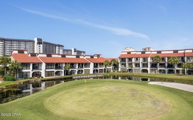 view of home's community with a water view and a lawn