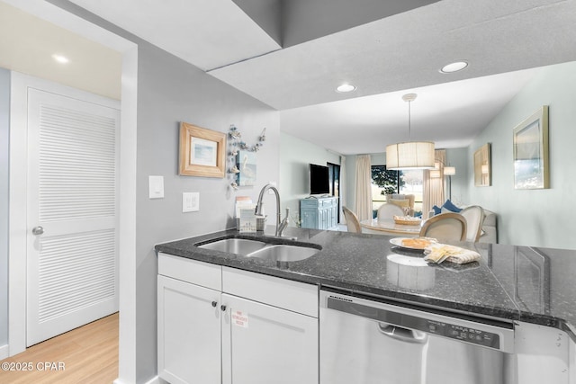 kitchen featuring dishwasher, sink, white cabinets, hanging light fixtures, and light hardwood / wood-style flooring