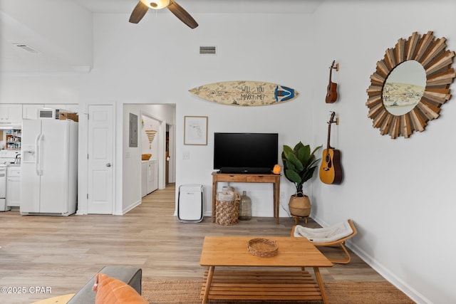 living room with ceiling fan, electric panel, washing machine and dryer, and light wood-type flooring