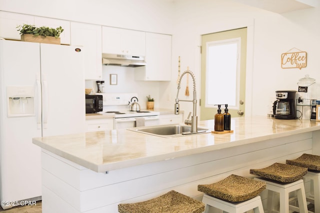 kitchen with sink, white appliances, white cabinetry, a kitchen breakfast bar, and light stone counters