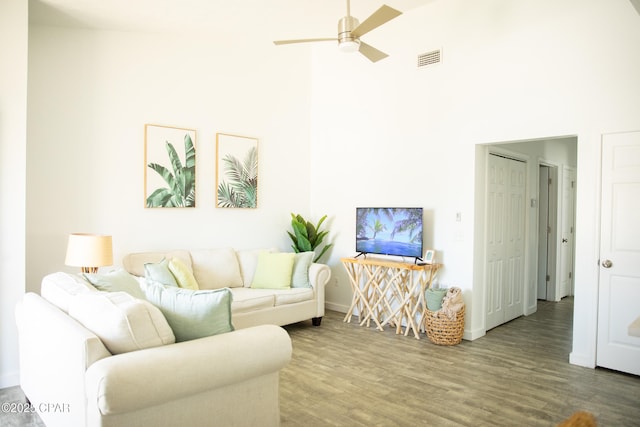 living room with wood-type flooring, ceiling fan, and a high ceiling