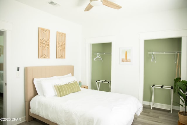 bedroom featuring hardwood / wood-style floors, multiple closets, and ceiling fan