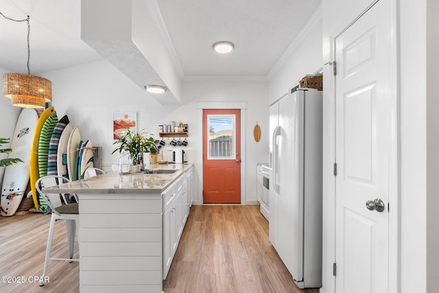 kitchen with a breakfast bar, white cabinetry, light wood-type flooring, hanging light fixtures, and white appliances