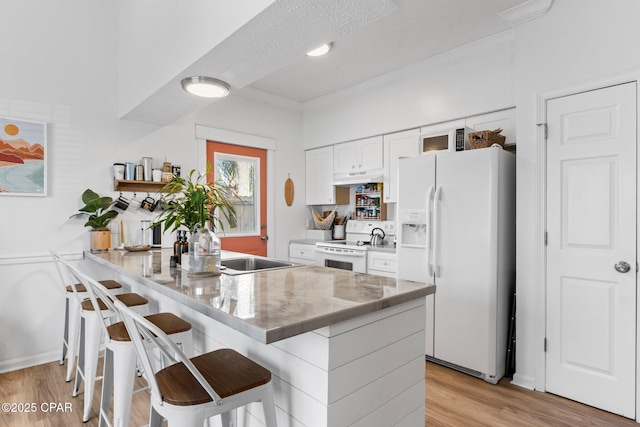 kitchen featuring white appliances, a breakfast bar, light hardwood / wood-style floors, ornamental molding, and white cabinets