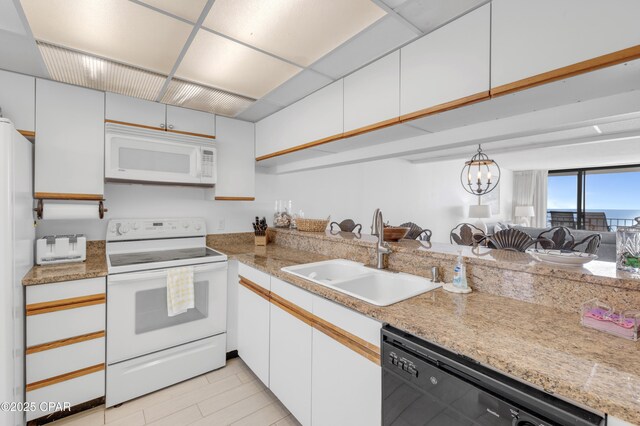 kitchen with an inviting chandelier, white appliances, sink, and white cabinets