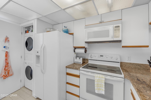 kitchen with stacked washer and dryer, stone countertops, white cabinetry, white appliances, and a paneled ceiling