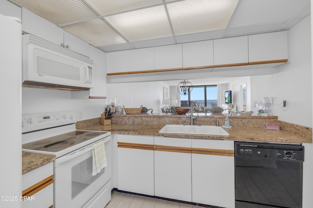 kitchen featuring white appliances, white cabinets, and a sink