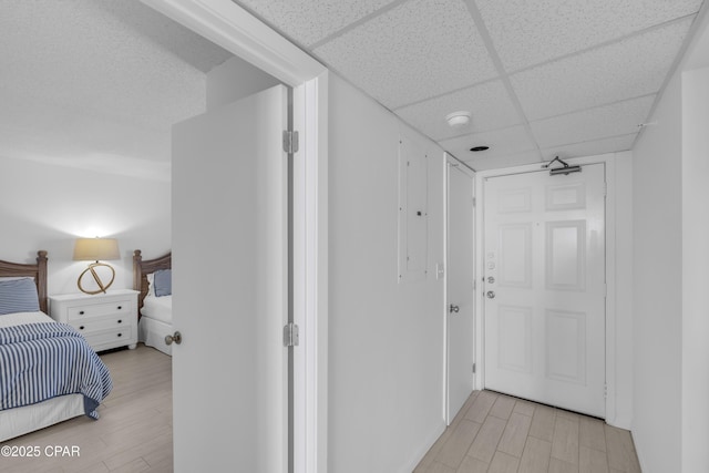 hall with light hardwood / wood-style flooring and a paneled ceiling