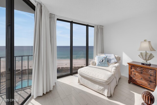 bedroom with a water view, expansive windows, access to exterior, and a textured ceiling