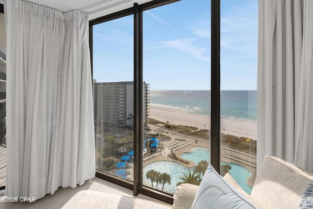 living area featuring a beach view, a wall of windows, and a water view