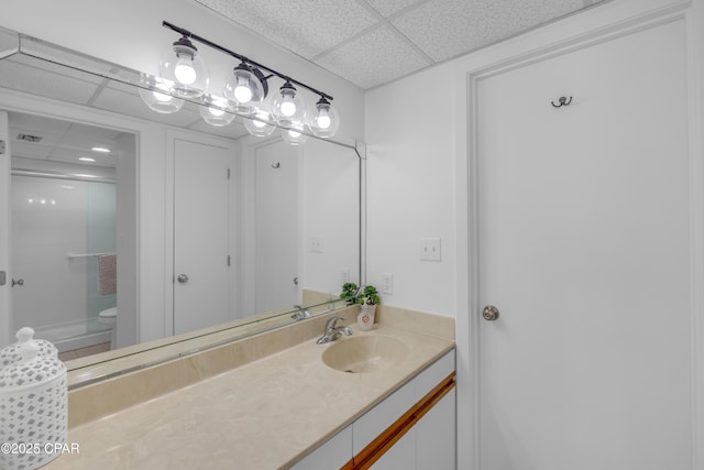 full bathroom with vanity, toilet, a drop ceiling, and walk in shower