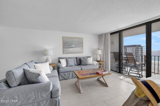 bedroom featuring light wood-type flooring, expansive windows, access to exterior, a water view, and a textured ceiling