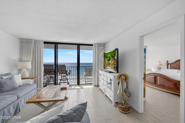 living room featuring a wall of windows, a textured ceiling, and a water view